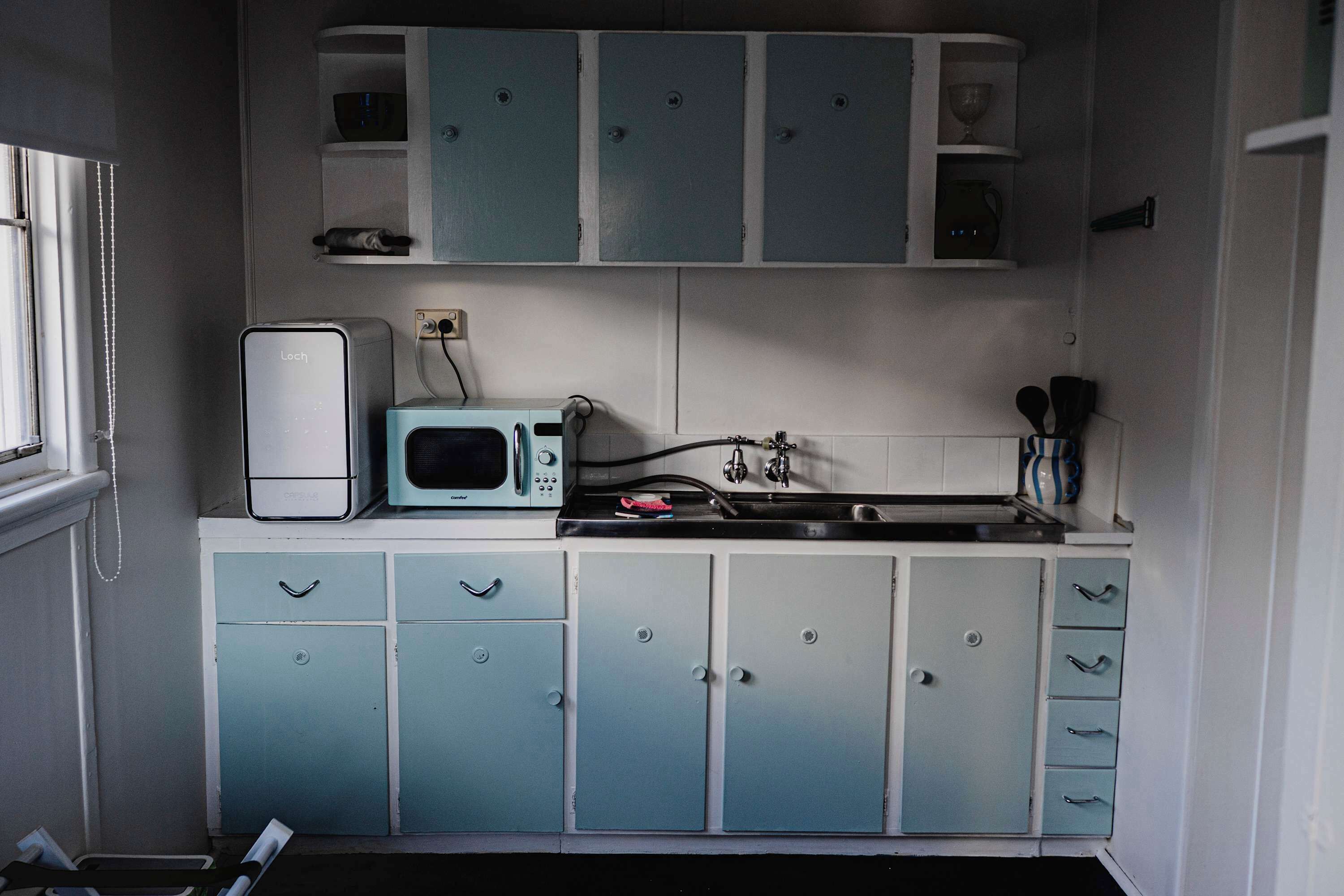 A compact kitchen with a microwave, a sink, and cabinets.