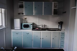 Eine kleine Küche mit Mikrowelle, Spüle und Schränken.