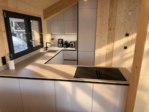 A modern kitchen with a large island, built-in appliances, and a view of the outside. - 02_NTH050_18a_Sup Chalet mit Sauna und Hot Tub 2 E by Interhome (Großveitsch)
