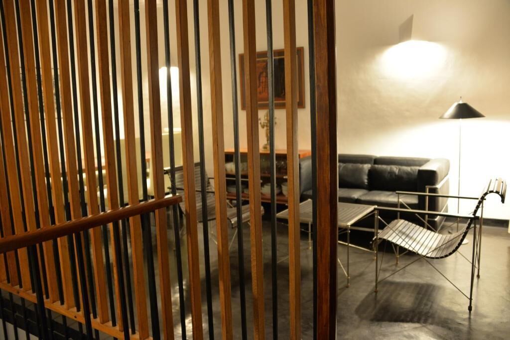 A room with a sofa, a table, and a chair. There is a wooden partition in the foreground.