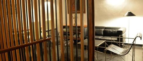 A room with a sofa, a table, and a chair. There is a wooden partition in the foreground.