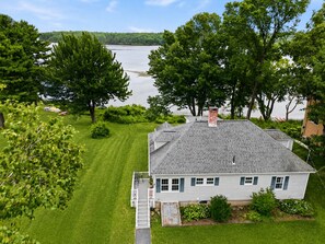 A house with a sloped roof, a front porch, and a view of a lake.