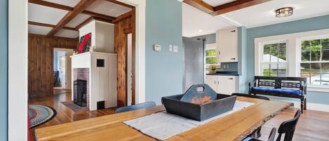 Uma sala de jantar com uma mesa de madeira, cadeiras e lareira.