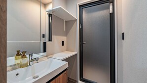Een moderne badkamer met een wit wastafelmeubel, spiegel en douche met een matglazen deur.