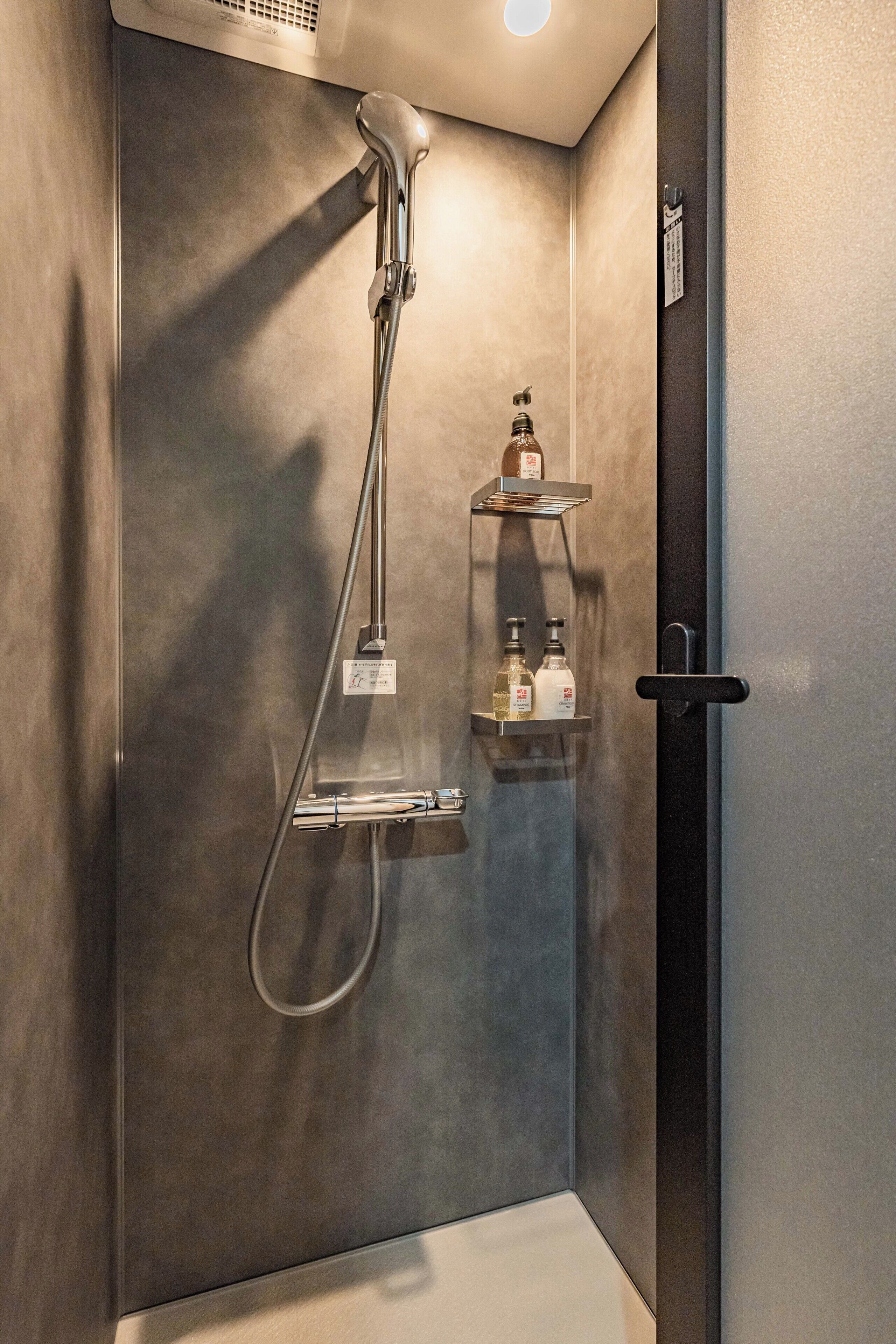 A modern shower with a handheld showerhead and a wall-mounted faucet.