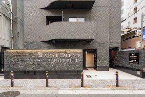 A modern building facade with a stone-textured wall and a sign for 'APARTMENT HOTEL II'. - Apartment Hotel11 Shinsaibashi AMEMURA 2 (Osaka-shi)