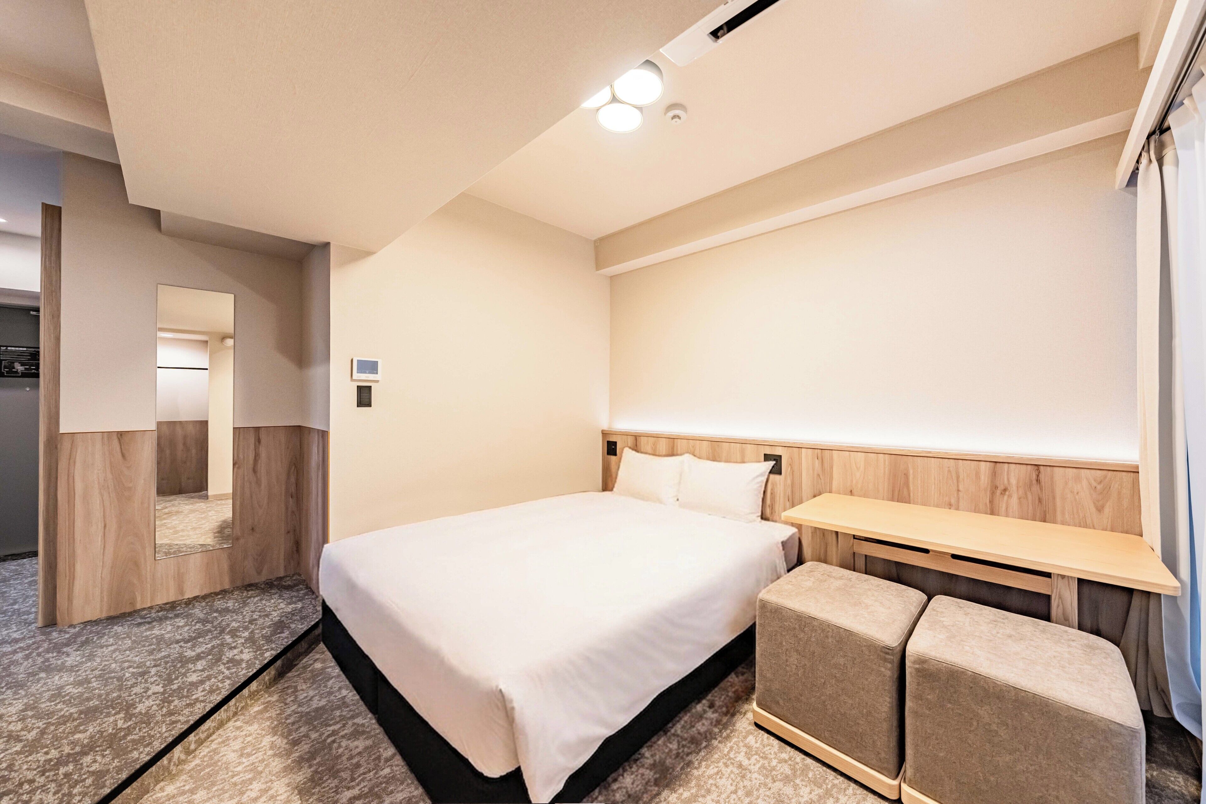 Ein Hotelzimmer mit einem Bett, einem Nachttisch, einem Spiegel und einer kleinen Sitzecke.