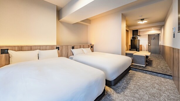 A hotel room with two beds, a wooden headboard, a carpeted floor, and a bathroom visible through an open door. - Apartment Hotel11 Shinsaibashi AMEMURA 2 (Osaka-shi)