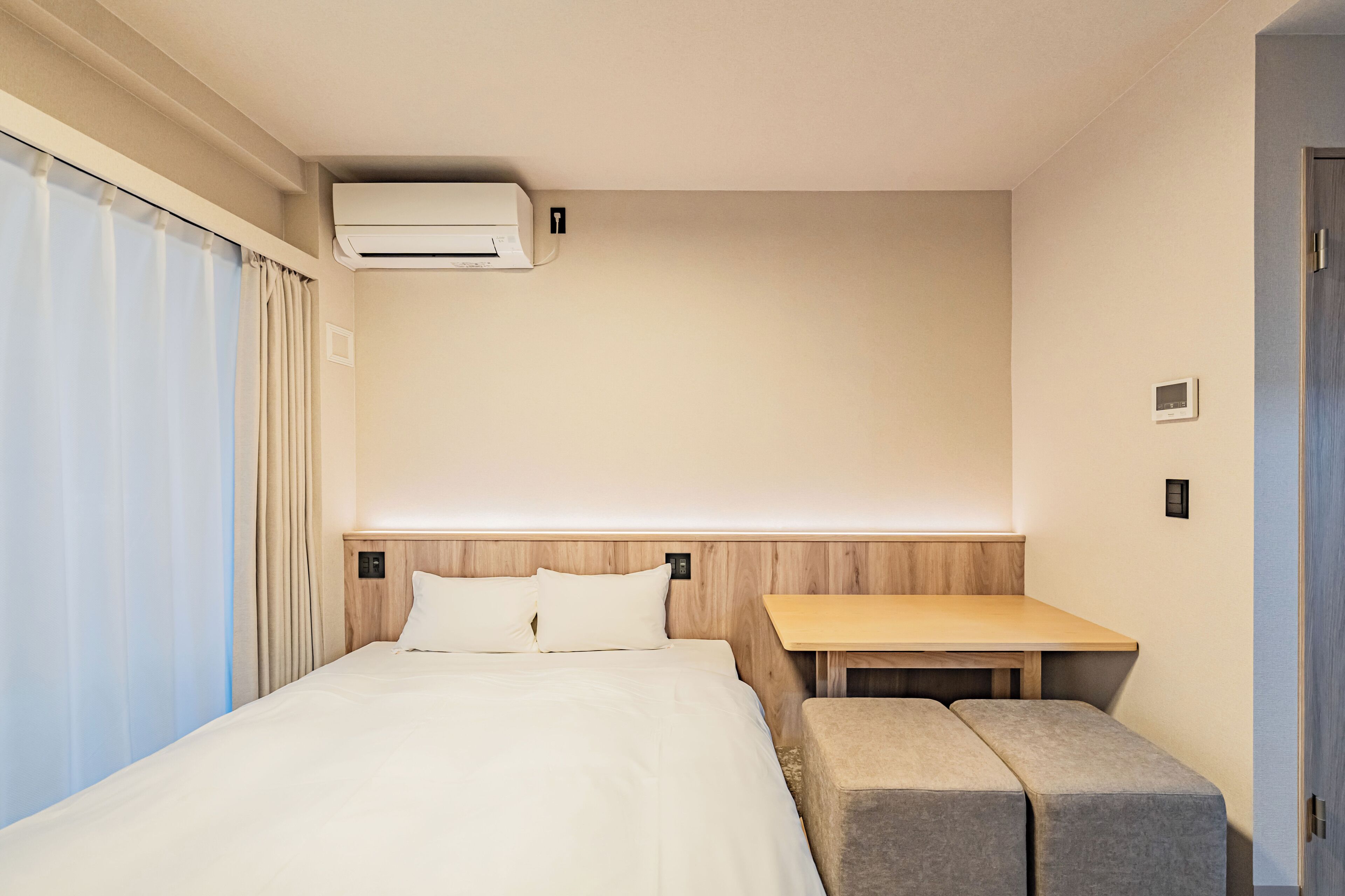 Una habitación de hotel con una cama, una mesita y un banco.