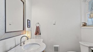 A bathroom with a marble sink, a toilet, and a window with a decorative item. - Bluish Cabin (Bucoda)