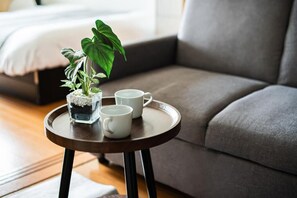 A small round table with a potted plant and two white mugs on a tray, placed on a wooden floor with a grey sofa in the background. - View Hakata 202 (Fukuoka City Hakataku HakataekiMinami)