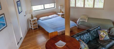 A room with a bed, a sofa, a table, and a window.