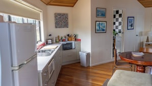 La cuisine est équipée d’un réfrigérateur, d’un évier et d’un plancher en bois. On y trouve également un coin repas avec une table et des chaises.