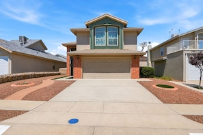 A residential house with a garage, a driveway, and a landscaped front yard.