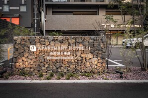 Eine Steinsäule mit einem Schild für 'APARTMENT HOTEL 11' und japanischen Schriftzeichen.