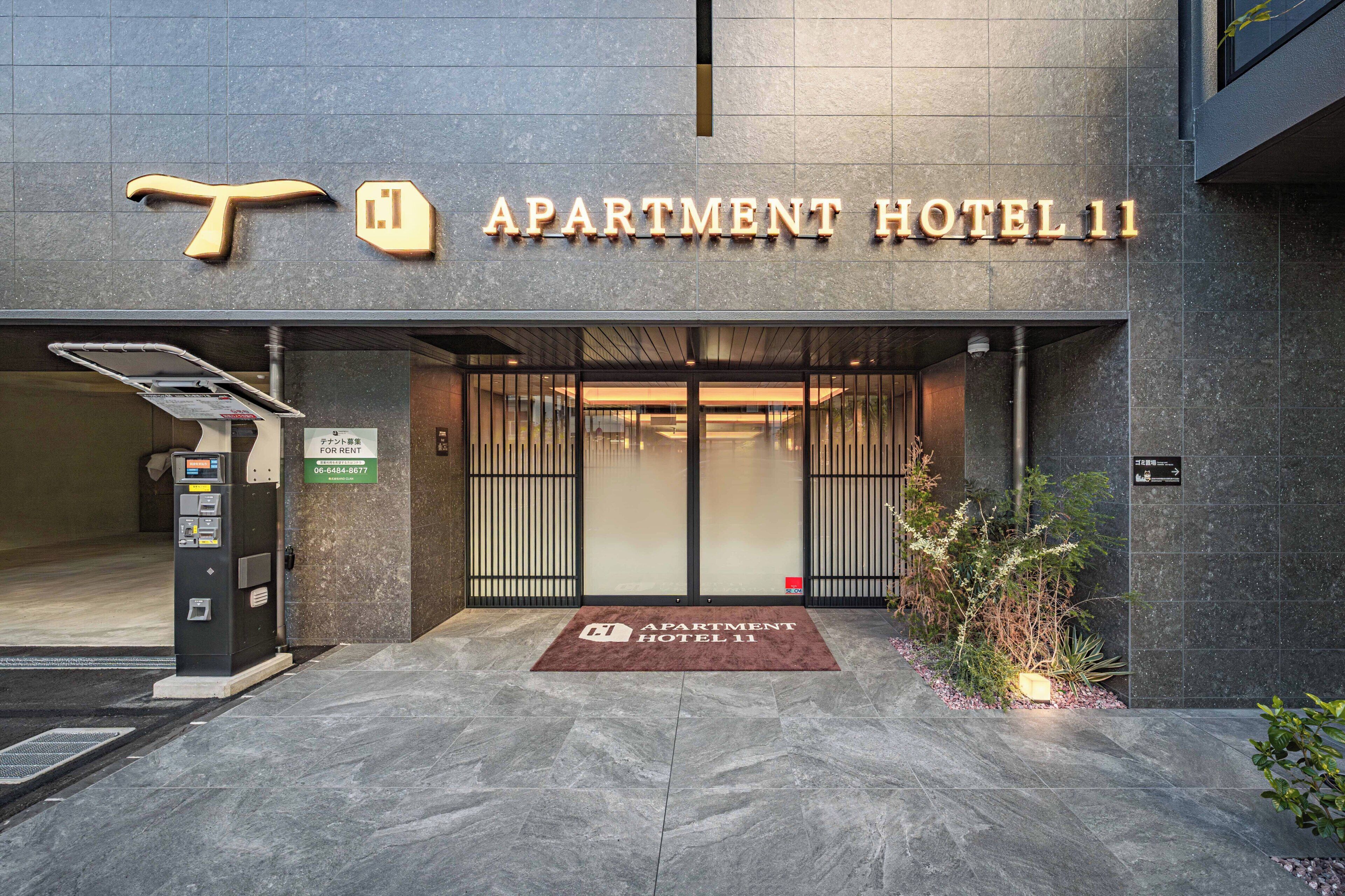 La entrada al Apartment Hotel 11, con un diseño moderno, un mostrador de recepción y un terminal de pago digital.