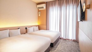 Quarto de hotel com duas camas, ar condicionado, televisão de tela plana e janela com cortinas.