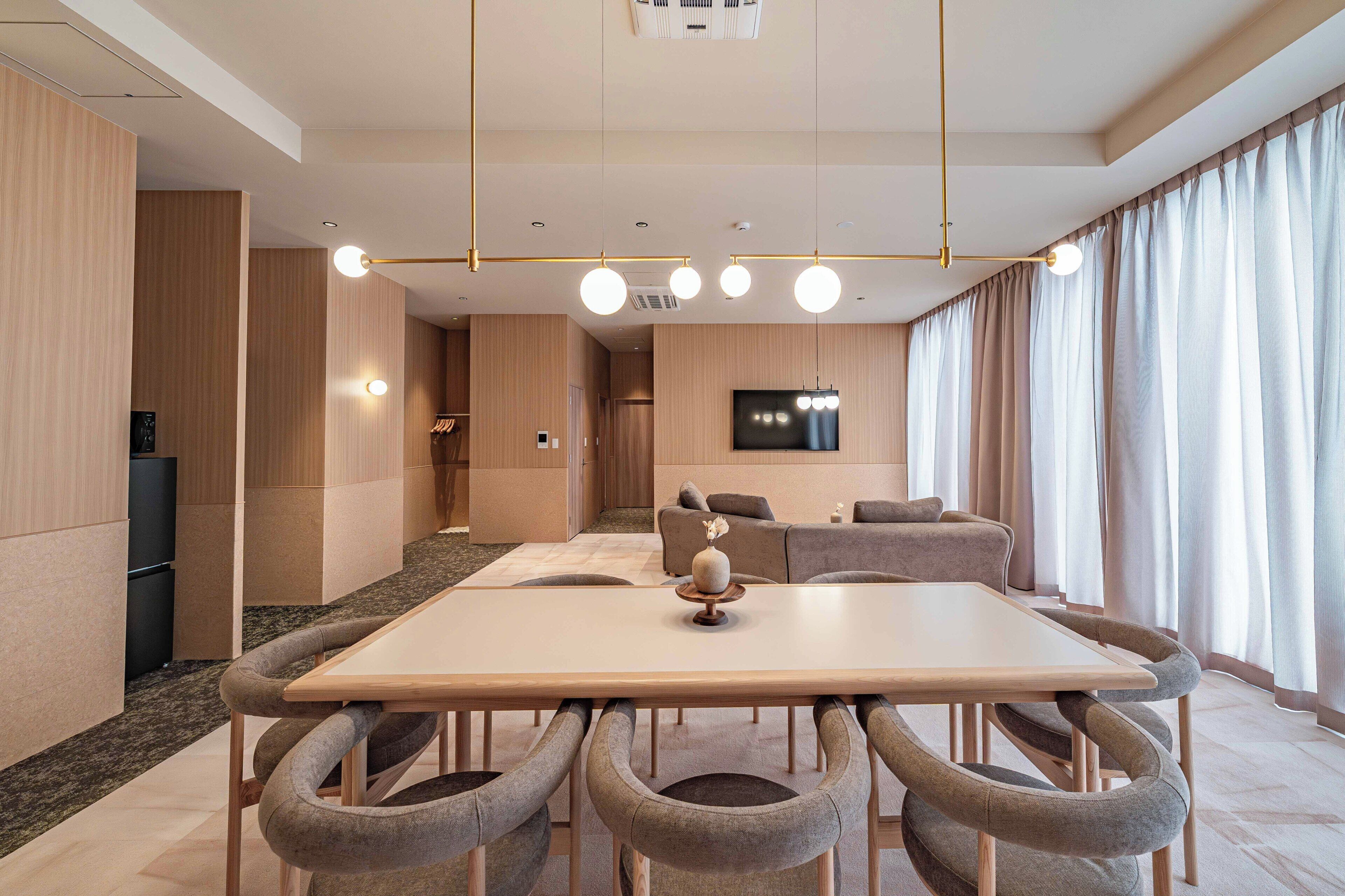 Habitación de hotel moderna con zona de comedor, televisión de pantalla plana y un amplio ventanal con cortinas.