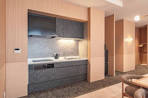 Uma cozinha moderna com eletrodomésticos embutidos, uma sala de jantar com mesa e cadeiras, e uma área de estar separada com um sofá.