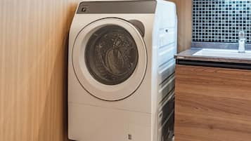 A front view of a compact, modern washing machine with a control panel on the top and a front-loading door.