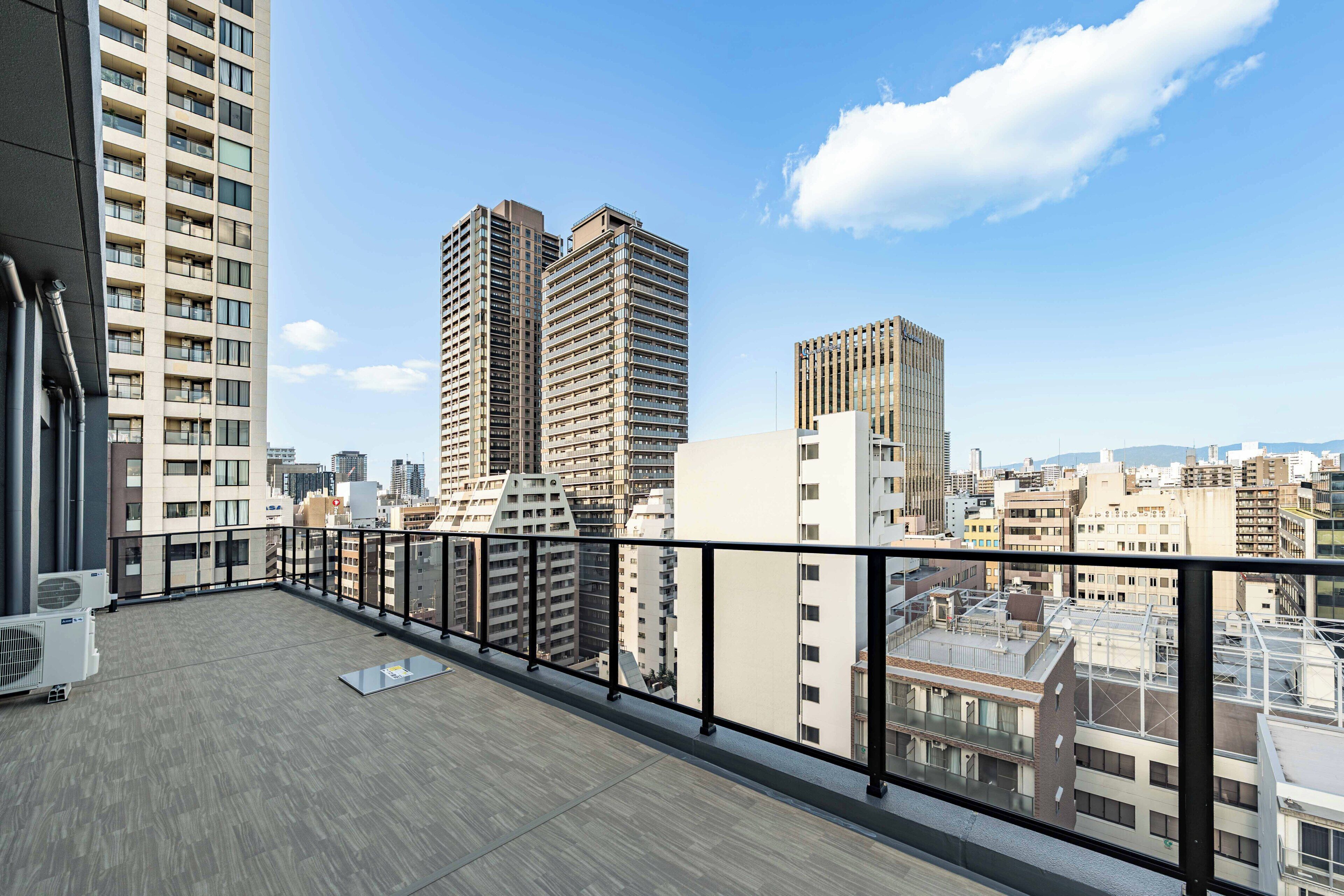 A high-rise building with a balcony overlooking a cityscape.