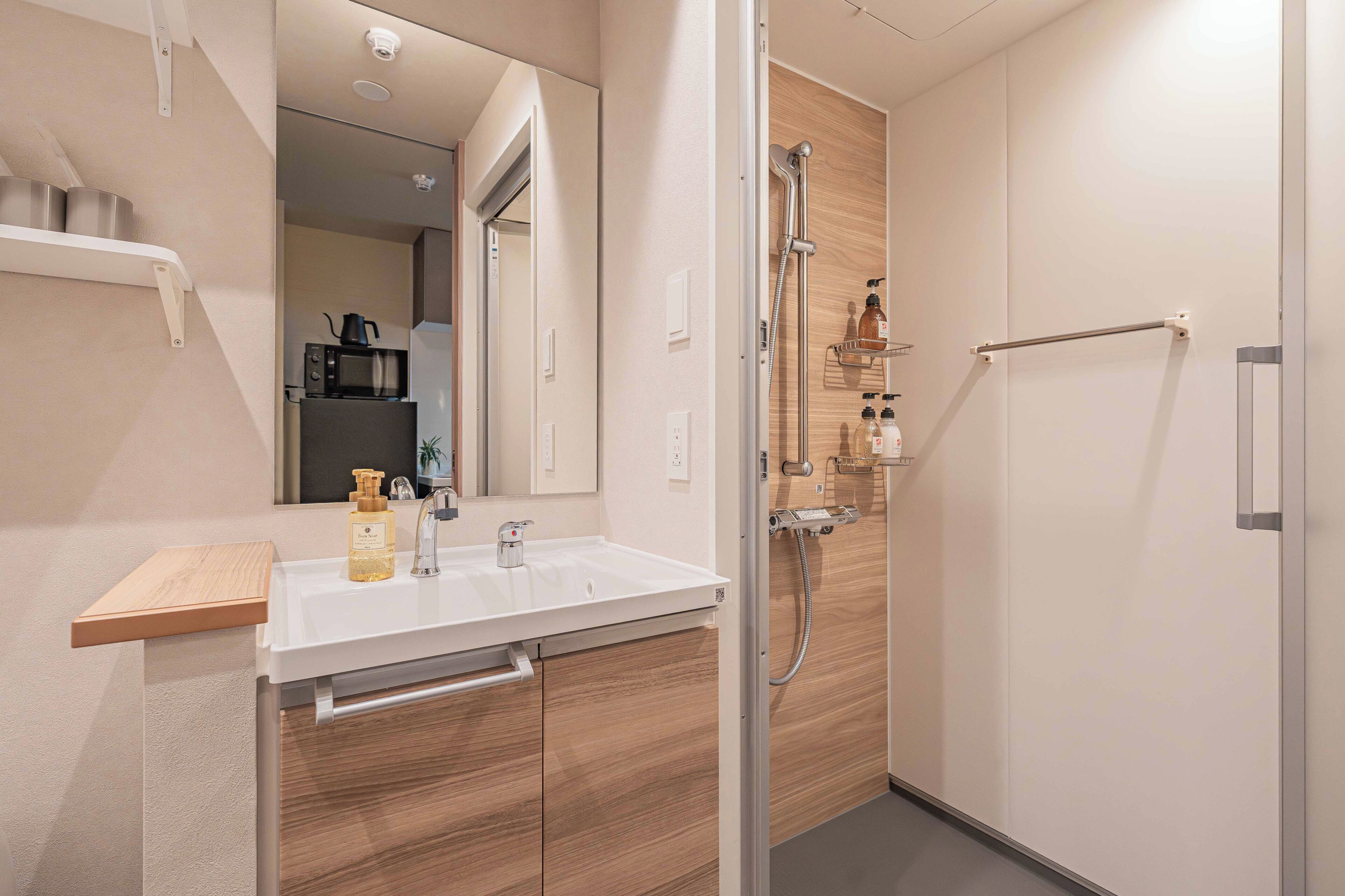 A modern bathroom with a shower, sink, and a microwave on the countertop.