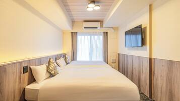 A hotel room with a large bed, a flat-screen TV mounted on the wall, and an air conditioning unit above the bed.