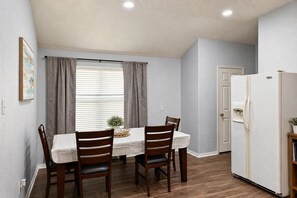 A dining area with a table and chairs, a window with curtains, a refrigerator, and a door. - North Houston 3 beds 2baths - Sleeps 8.
Professionals, Work Groups and Families! (Houston)