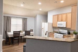 A compact kitchen with a dining area, wooden cabinets, a microwave, stove, and a small potted plant. - North Houston 3 beds 2baths - Sleeps 8.
Professionals, Work Groups and Families! (Houston)