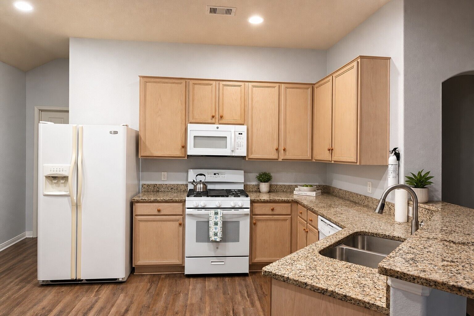 A kitchen with wooden cabinets, a white refrigerator, a microwave, a stove, and granite countertops.