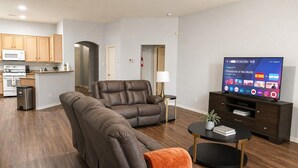 Ein modernes Wohnzimmer mit einem Ecksofa, einem Flachbildfernseher und einem kleinen Couchtisch.