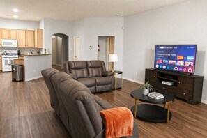 Ett modernt vardagsrum med en hörnsoffa, en platt-TV och ett litet soffbord.