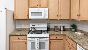 Eine Küche mit Holzschränken, einer Mikrowelle, einem Gasherd, einem Toaster und einem Wasserkocher.