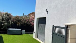 Un edificio residencial con fachada gris, un césped verde y una puerta de garaje gris cerrada.