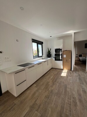 Eine moderne Küche mit weißen Schränken, einem eingebauten Backofen und einem großen Fenster.