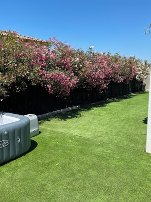 A well-maintained lawn with a hot tub and a row of flowering shrubs. - Maison spacieuse 4 chambres climatisées proche aéroport,gare tgv et plages (Les Pennes-Mirabeau)