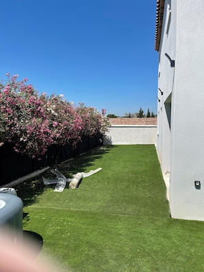 A well-maintained lawn with a white wall and a row of flowering bushes. - Maison spacieuse 4 chambres climatisées proche aéroport,gare tgv et plages (Les Pennes-Mirabeau)