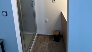 Un pasillo estrecho con una puerta de cristal que da a una zona de ducha.