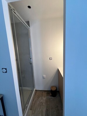 Ein schmaler Flur mit einer Glastür zu einem Duschbereich.