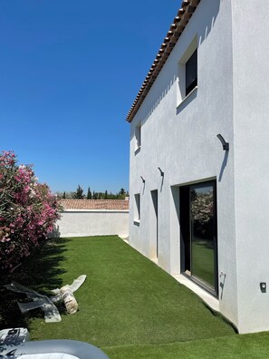 Ein modernes Gebäude mit weißer Fassade und einem Ziegeldach, einem grünen Rasen und blauem Himmel.