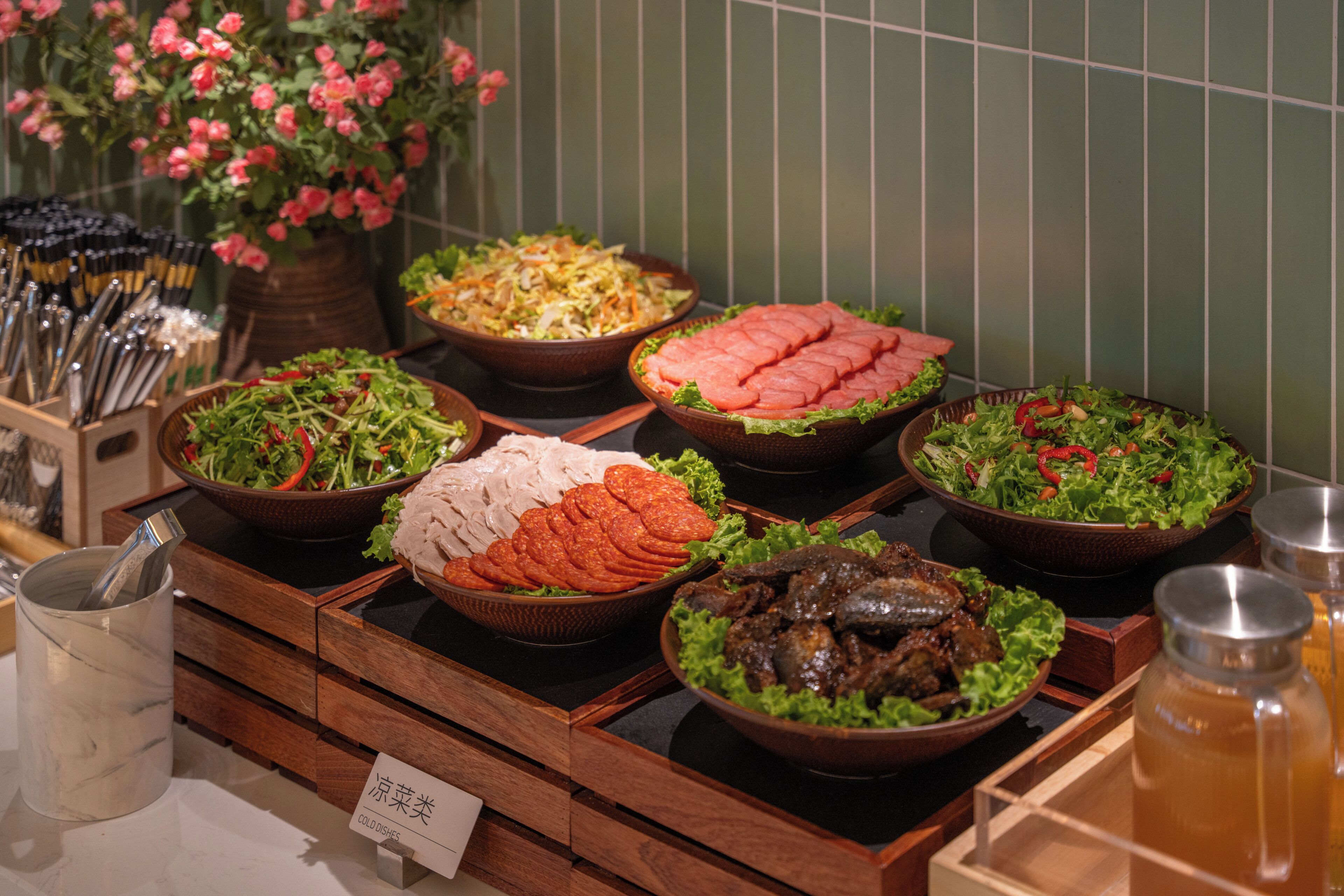 Un bufé con diversos platos fríos, entre ellos ensaladas, carnes y mariscos.