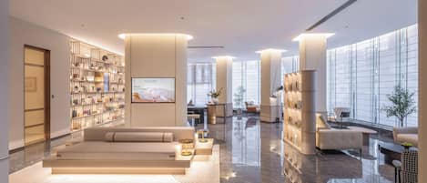 A spacious lobby with a seating area, a bookshelf, and a large window providing a view.