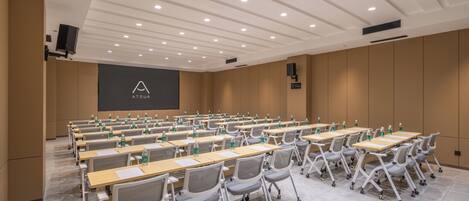 A conference room with rows of tables, chairs, and a projection screen.