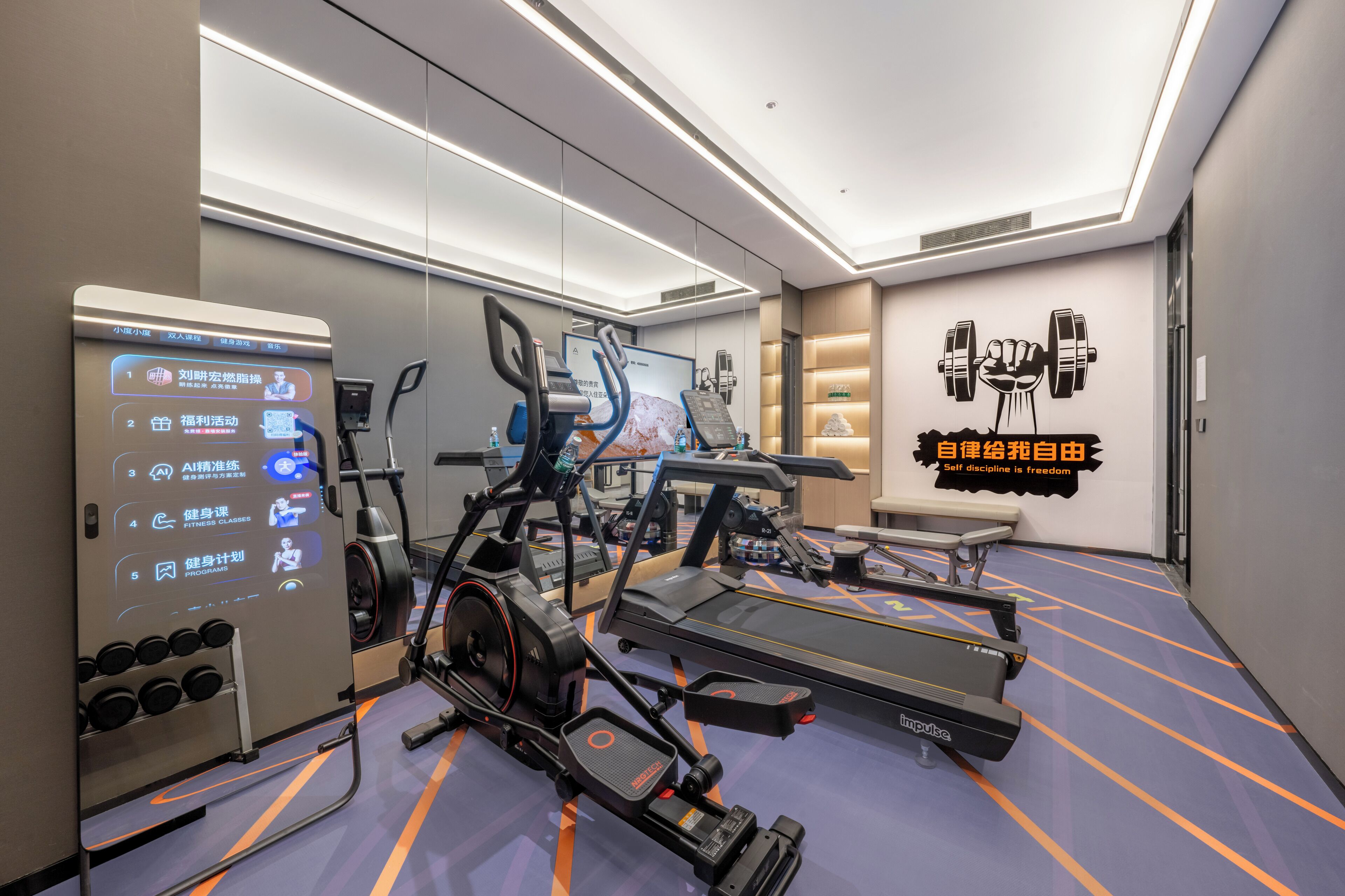 A modern fitness room with exercise equipment, a digital interface, and motivational wall art.
