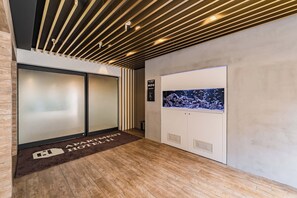 Un vestíbulo de hotel con una recepción, una pantalla digital de acuario y un suelo de madera.