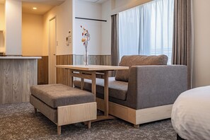 Ein gemütliches Hotelzimmer mit einer Couch, einem kleinen Tisch und einer Zierdevasse.