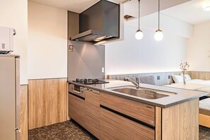 A modern kitchen with a built-in stove, a stainless steel sink, and wooden cabinetry. - Apartment Hotel 11 Nambaminami 6 (Osaka-shi)