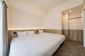 Habitación de hotel con una cama grande, cabecera de madera, mesita de noche pequeña y una lámpara de pared.