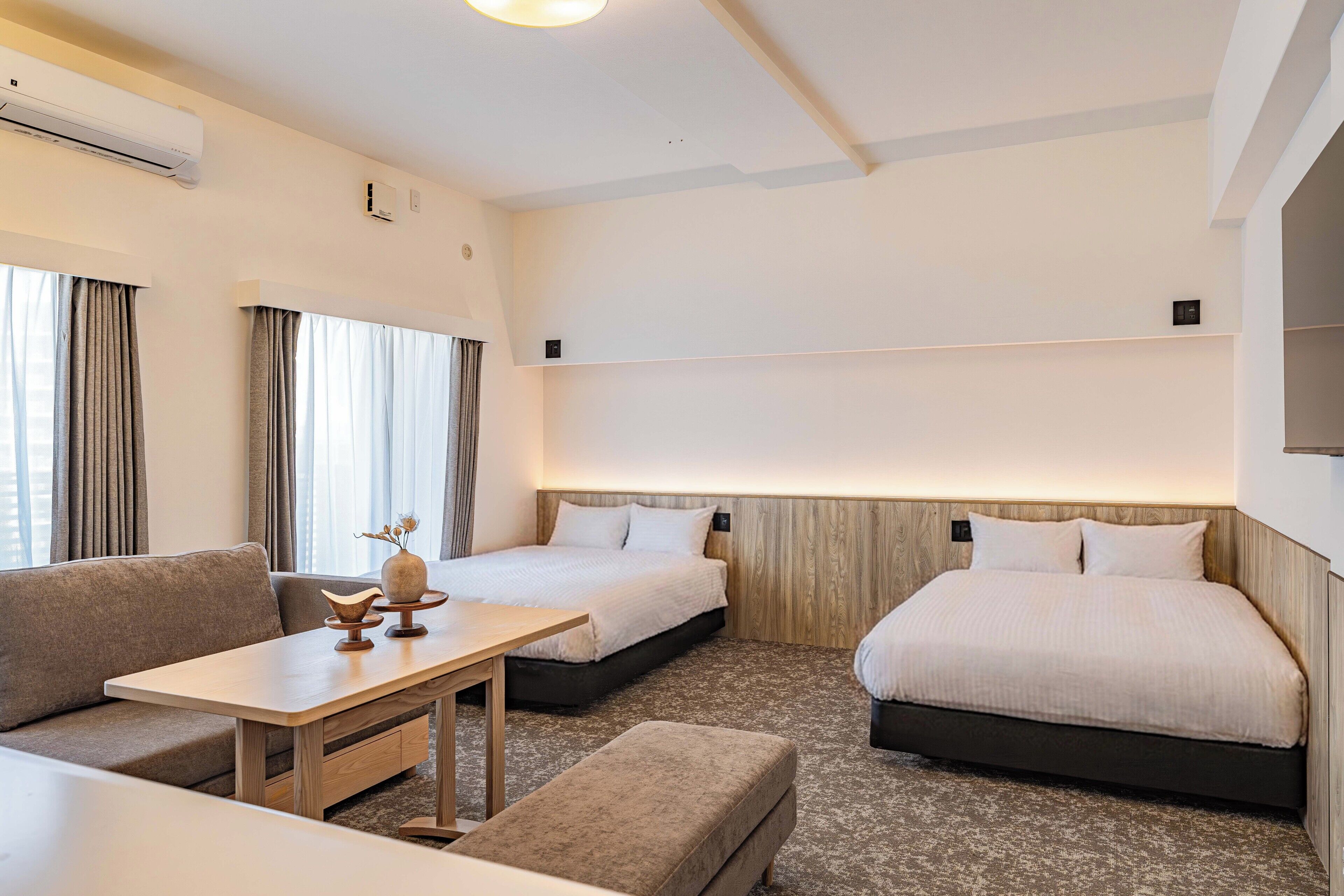 Ein Hotelzimmer mit zwei Betten, einer Couch, einem kleinen Tisch und einem Fernseher.