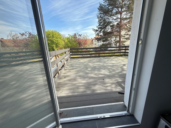 A view from a room with a sliding glass door leading to an outdoor deck with a wooden railing. - FeWo Südstadt Kassel (Kassel)